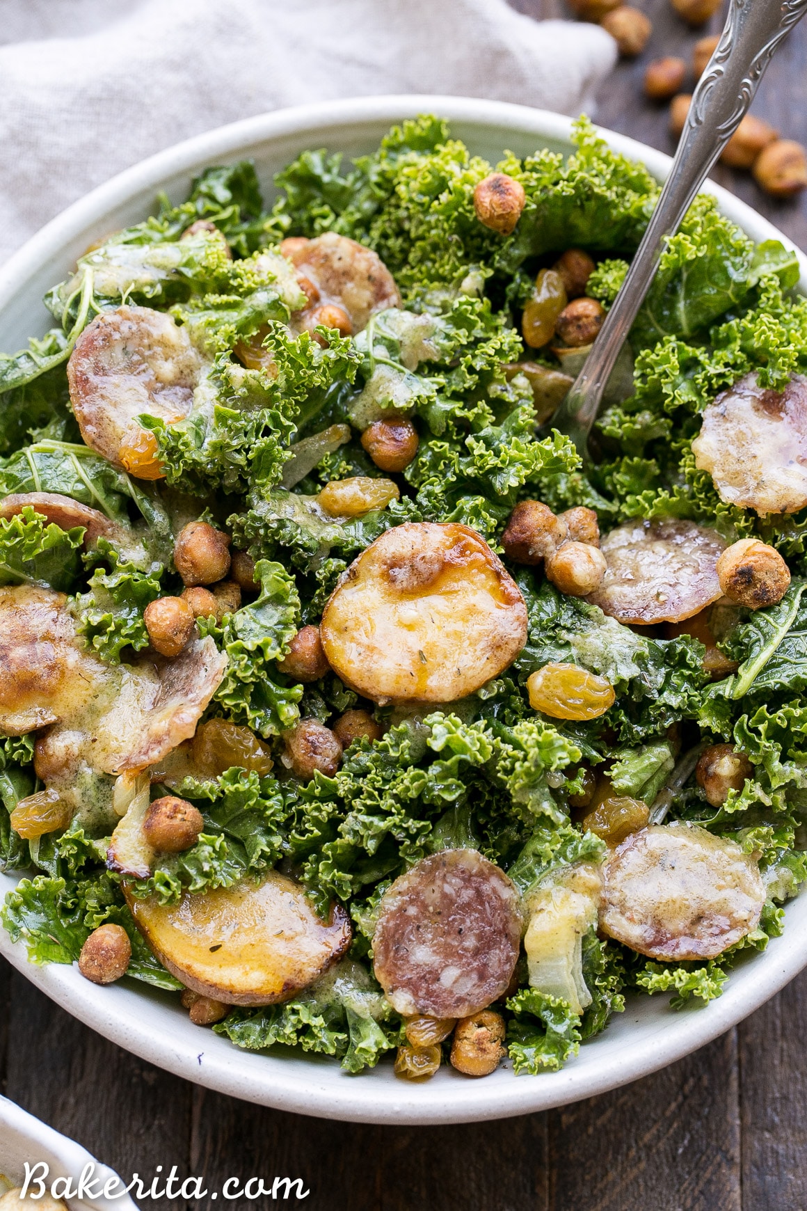 This Kale & Salami Salad with Roasted Garlic Vinaigrette is loaded with roasted fingerling potatoes, crispy toasted chickpeas, golden raisins, and caramelized onions! This filling salad makes the perfect lunch or dinner. It's gluten free and dairy free, with a Paleo option.