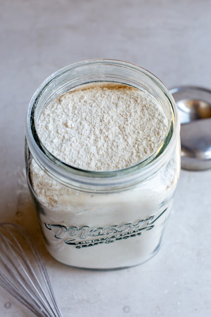 Gluten-Free Bread Flour Blend in a large mason jar with a whisk in the foreground, shot from overhead.